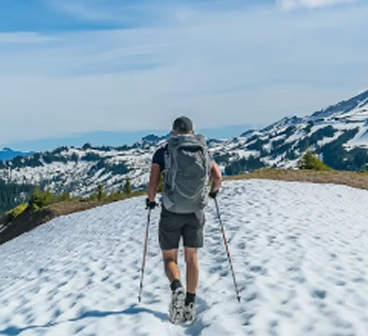 Backpacker walking on snowy mountain trail